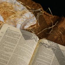 Bible next to straw and white cloth. 